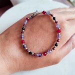 Bransoletka znak zodiaku Skorpion - Ametyst, Hematyt, Turmalin czarny, Granat i Jadeit Rubinowy 4 Delikatna bransoletka z kolorowych kamieni naturalnych na kobiecej dłoni.