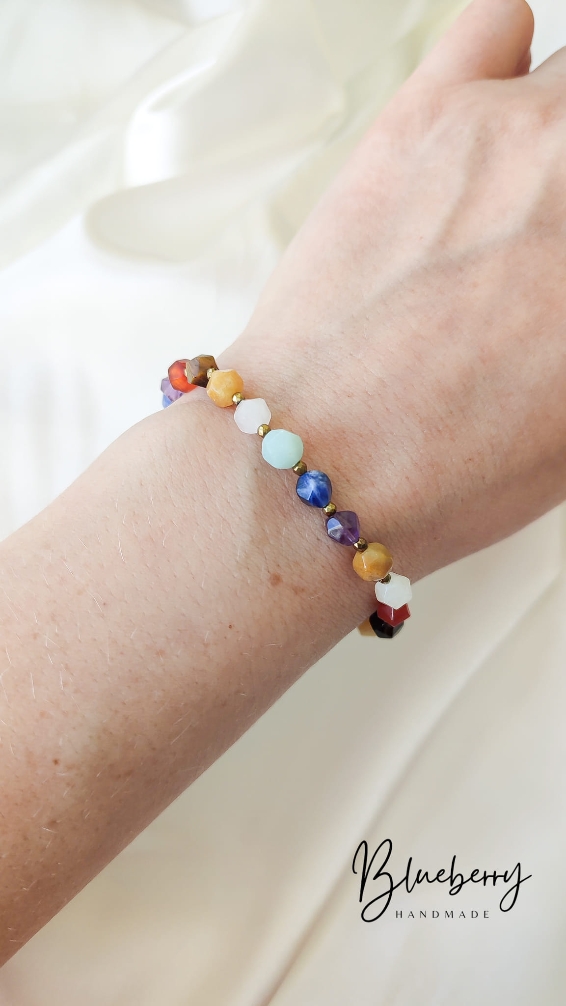 Tęczowa Bransoletka Handmade z Kamieni Naturalnych Tęczowa bransoletka handmade z drobnych kamieni naturalnych na kobiecym nadgarstku.