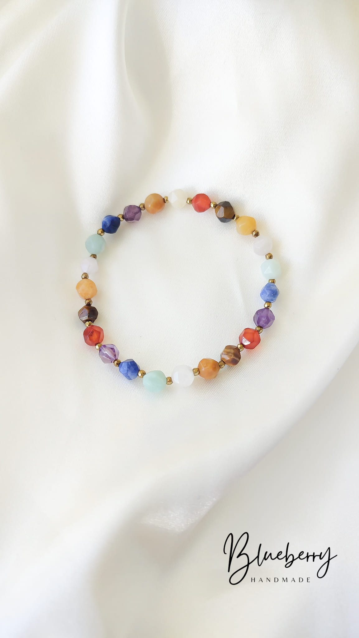 Tęczowa Bransoletka z Kamieni Naturalnych Handmade Tęczowa bransoletka handmade z kamieni naturalnych na białym satynowym tle.