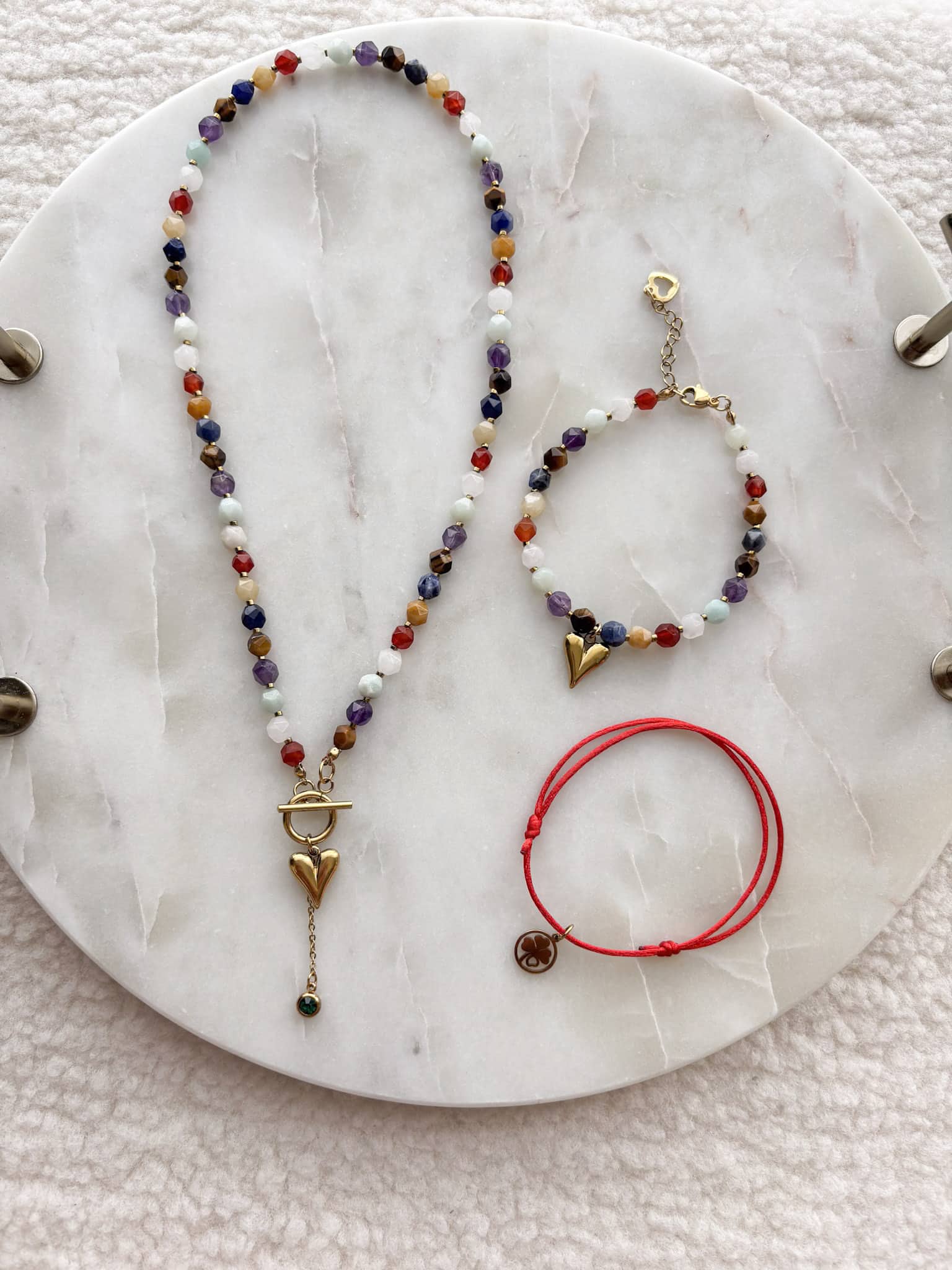 Zestaw biżuterii handmade boho Zestaw biżuterii handmade boho: kolorowy naszyjnik i bransoletki na marmurowej tacy.