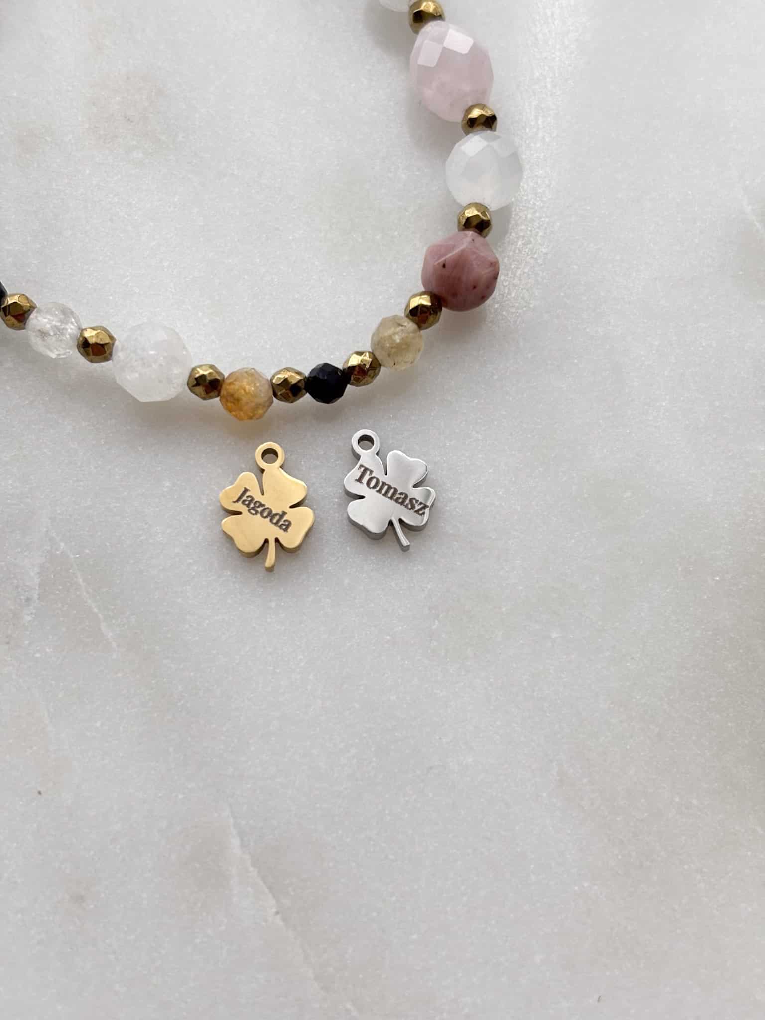 Personalizowana bransoletka z kamieni z grawerowanymi zawieszkami w kształcie koniczynek.