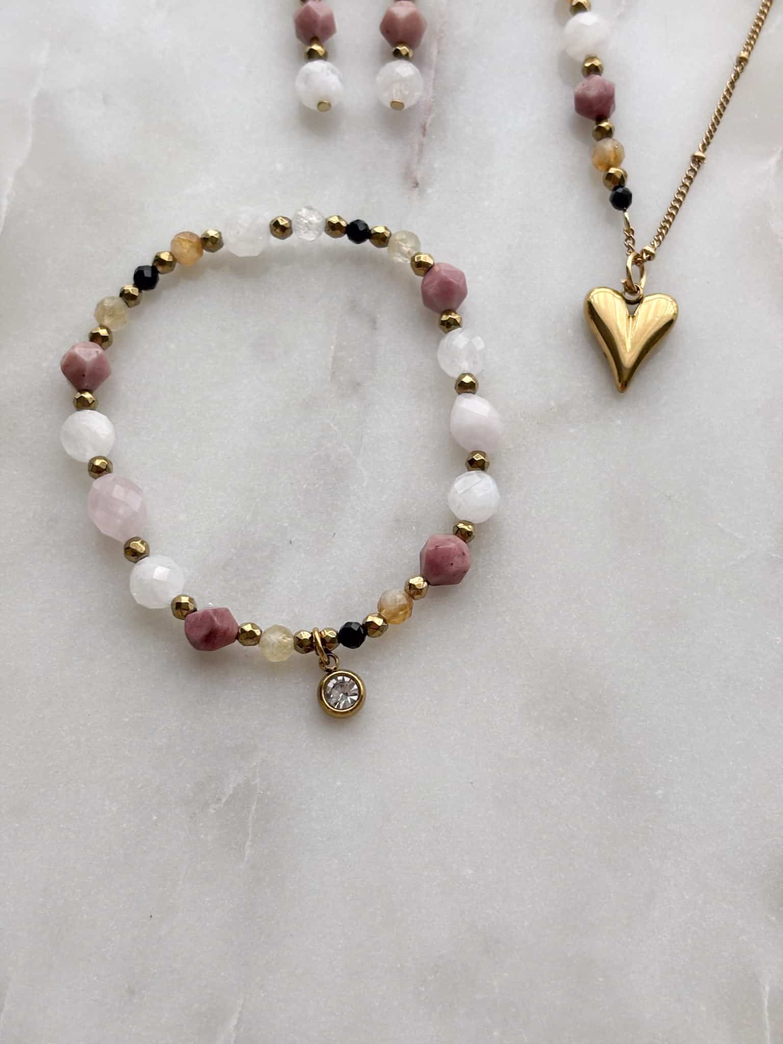 Różowy komplet biżuterii handmade: bransoletka, naszyjnik ze złotym sercem i kolczyki.